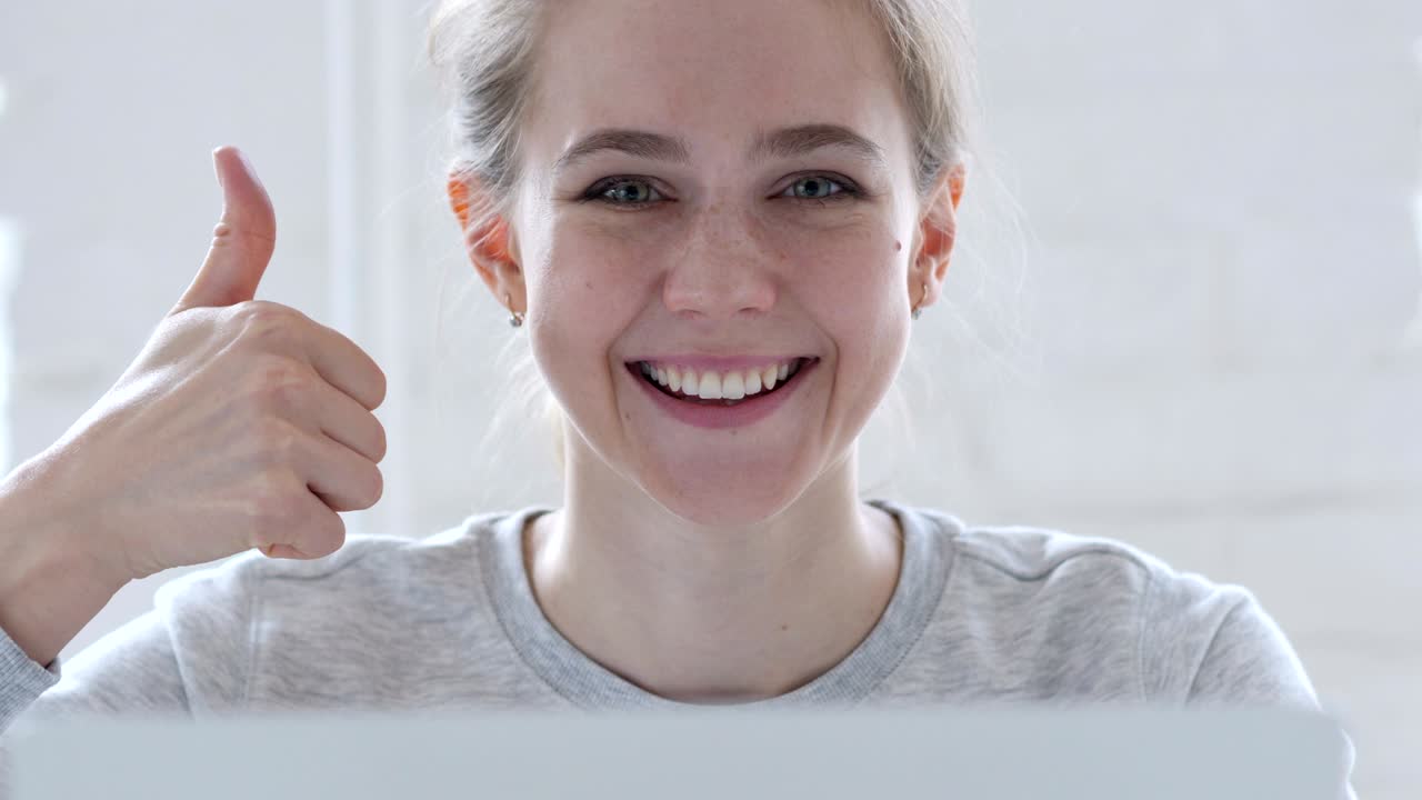 Thumbs Up by Young Woman Working on Laptop