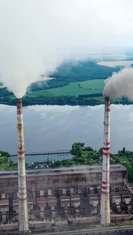 drone shot of industrial zone with thick smog and burning fossil fuels. factory zone pan shot left to right of polluted city, many factory chimneys in city area. vertical video