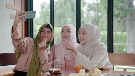 group of muslim girls dining in a restaurant is using their mobile phones to chat online with their friends on social media, hangout with friends for drinks and meals after the end of ramadan.