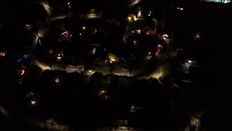driving car on street of quiet residential area in america. night scene in neighborhood with lighting streetlamps. aerial view. houses and homes in suburb.