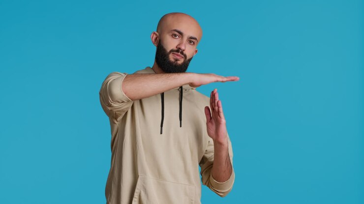 Persona del Medio Oriente che fa il gesto del timeout davanti alla telecamera