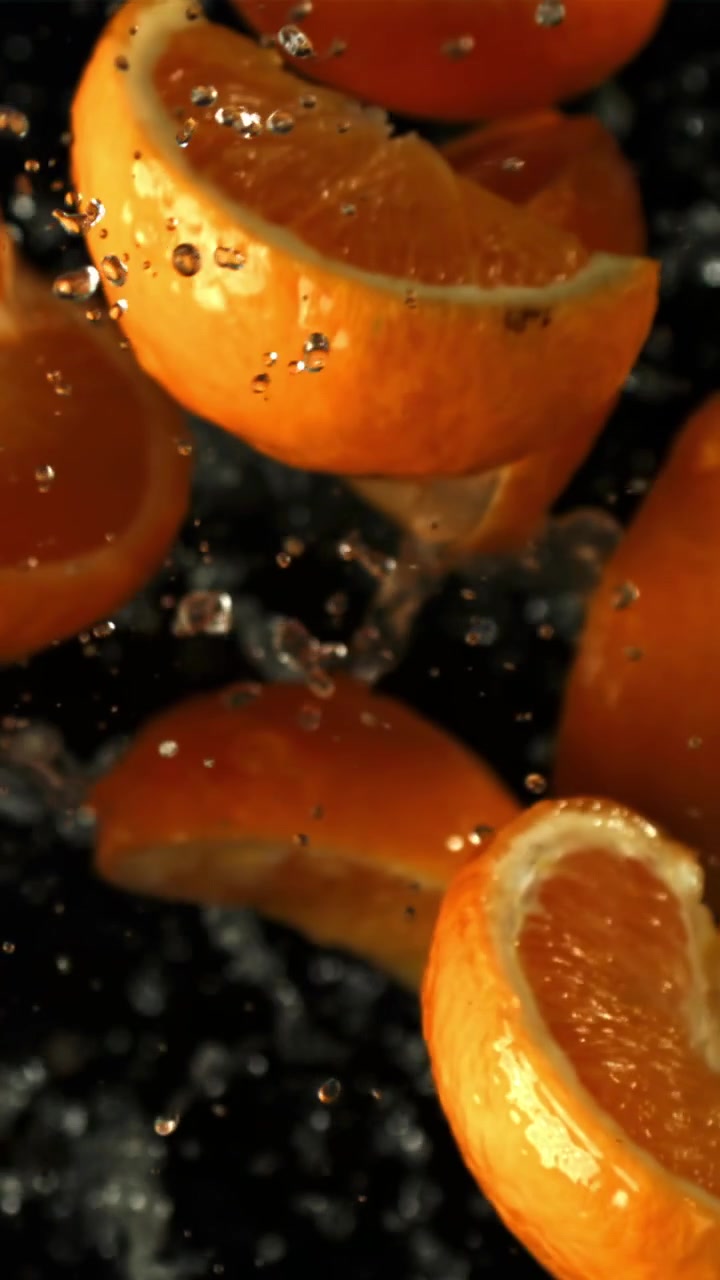 Fette d'arancia vivaci e goccioline d'acqua che cadono al rallentatore
