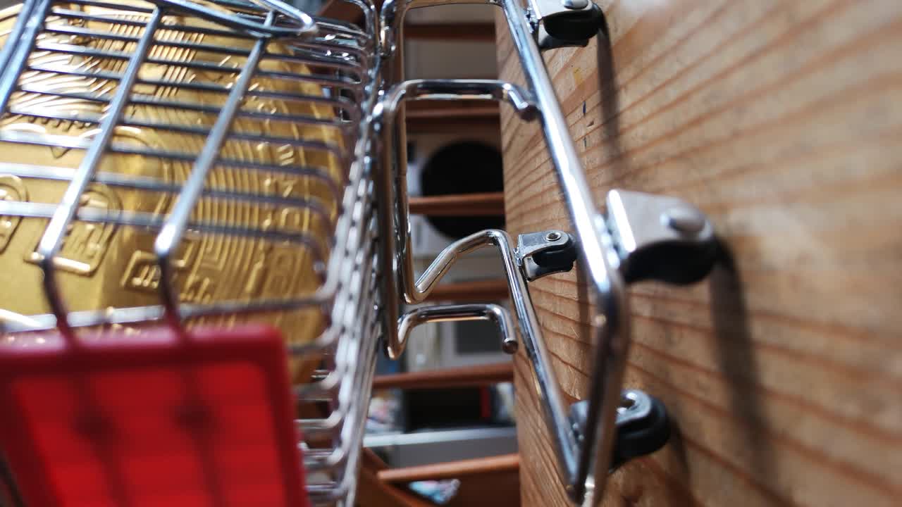 세로 클립:부엌 테이블 개념의 작은 쇼핑 카트에 있는 금색 비트코인 암호화 통화 낮은 각도 반전 샷