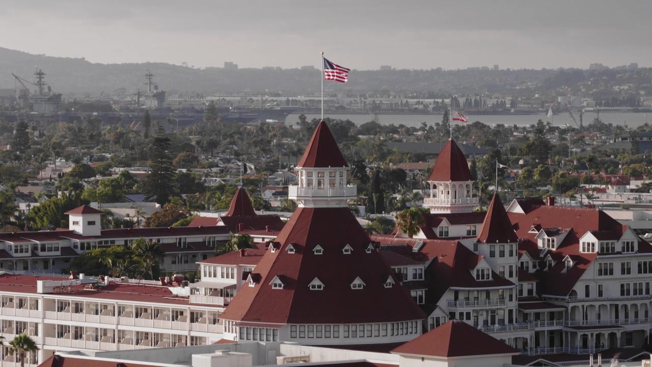 Vista aerea ravvicinata mozzafiato da drone dell'architettura dell'isola di Coronado con navi della Marina nella baia di San Diego - (UHD 4K)
