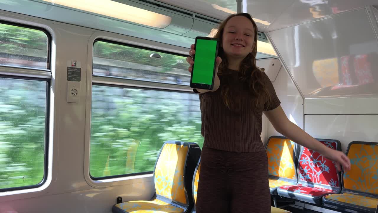 십대 소녀는 그녀의 손에 크로마 키와 함께 녹색 화면을 들고, 춤을 추고, 미소 짓고, 프레임을 바라보고, 클래스를 보여주고, 매우 기니다.