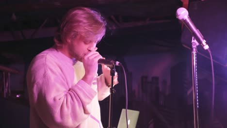 atlanta, ga - december 15, 2018: a male r-b singer with long blond hair, wiley from atl, sings passionately during a lively concert in an underground urban nightclub popular with millennials.