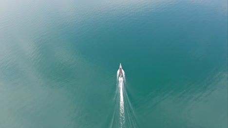 drone footage of long-tail boat sailing, crystal clear blue water