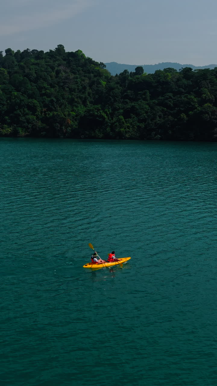 Persone che vanno in kayak su un lago sereno circondato da una foresta lussureggiante