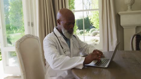 African-american-senior-male-doctor-using-laptop-at-home