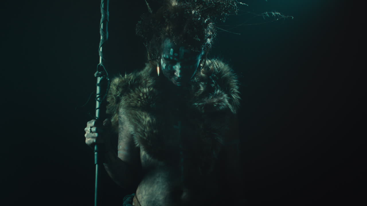 A creepy witch stands in the moody pose during the night storm