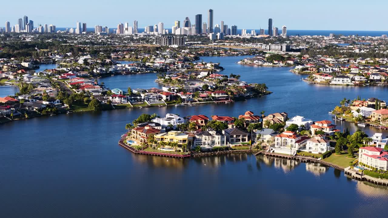 High-resolution drone footage glides over luxury waterfront estates, river inlets, and urban skyline under bright daylight in Gold Coast, Australia