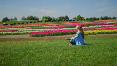 young woman meditating on green grass. hipster girl sitting in lotos outdoors.