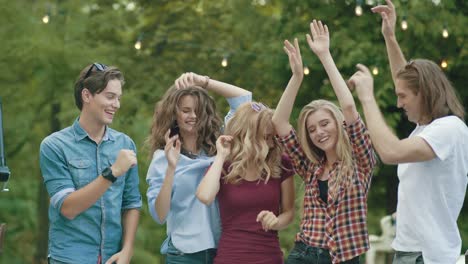 happy friends dancing, having fun and enjoying party outdoors.