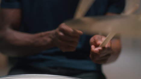 crop black musician playing drums in evening unrecognizable african american guy playing drums during music session in evening at home