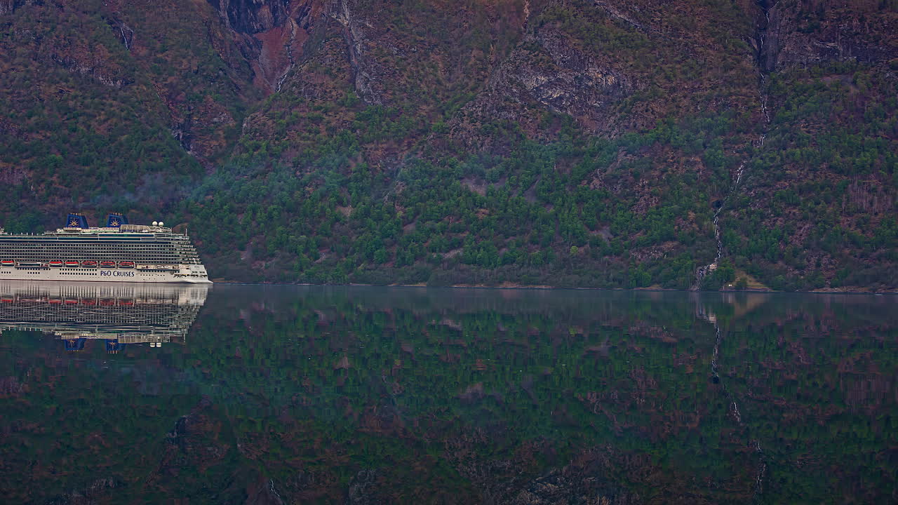 거대한 산들을 배경으로 피요르드를 통과하는 유람선의 시간 경과