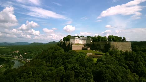 Beautiful-aerial-footage-of-drone-descending-and-moving-back-from-a-landmark-castle-on-the-thill-in-the-middle-of-Europe-on-a-partly-cloudy-day