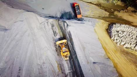 aerial view of bulldozer and dump truck operating at a quarry or construction site