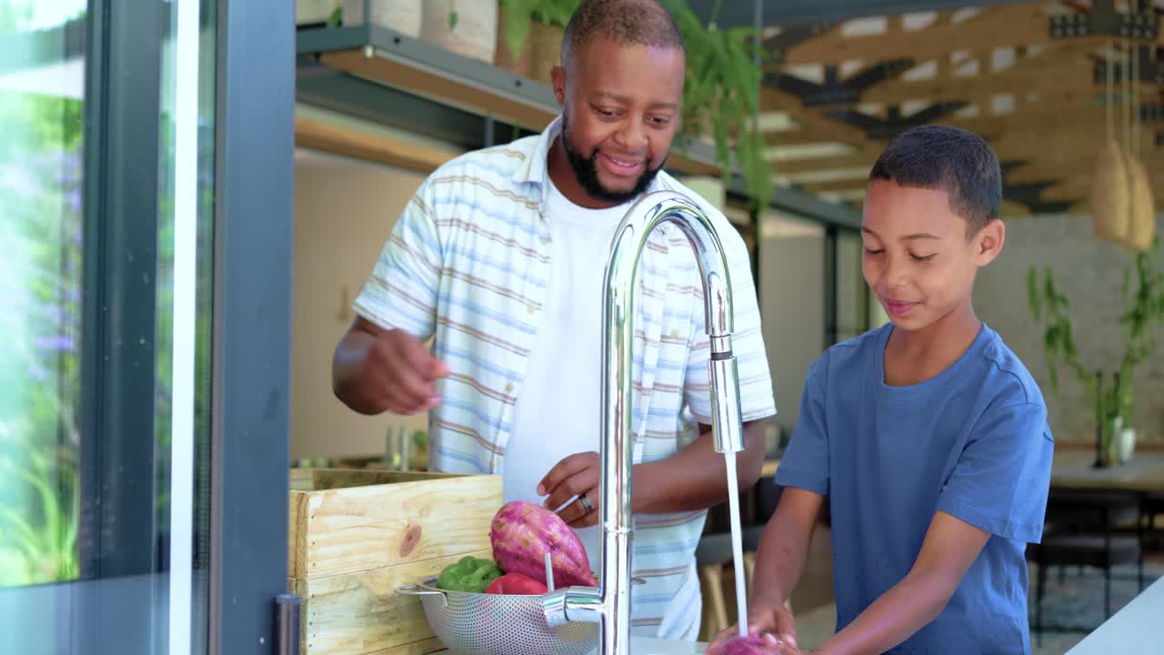 African American father arriving, assisting youth son rinsing purple roots at chrome tap for meal