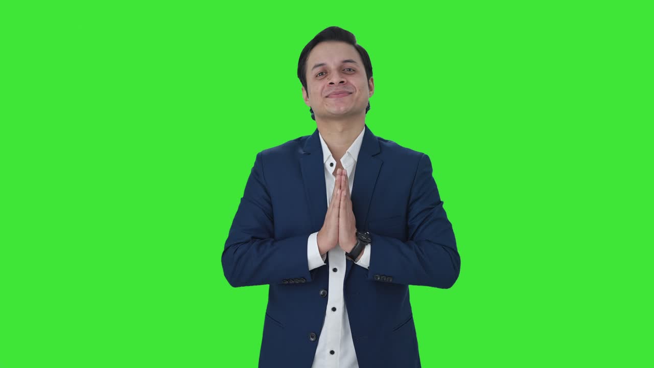 Happy Indian businessman doing Namaste Green screen