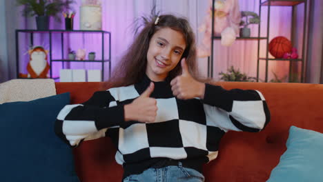 una joven feliz mirando con aprobación a la cámara mostrando los pulgares hacia arriba, como un signo positivo, buenas noticias