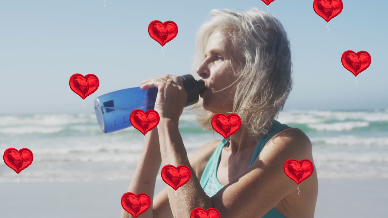 animación de globos de corazón rojo que se elevan sobre la mujer bebiendo agua en la playa