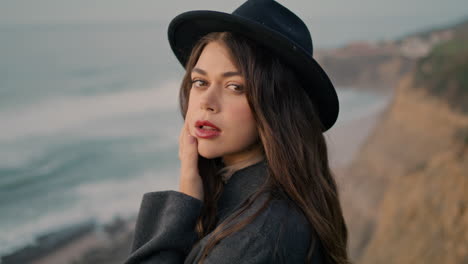 gentle young woman portrait standing in front gloomy seashore looking camera.