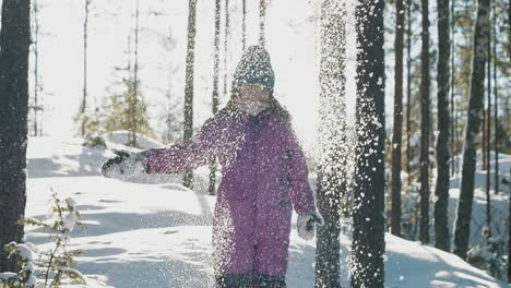 niño feliz arrojando nieve al aire en un día soleado