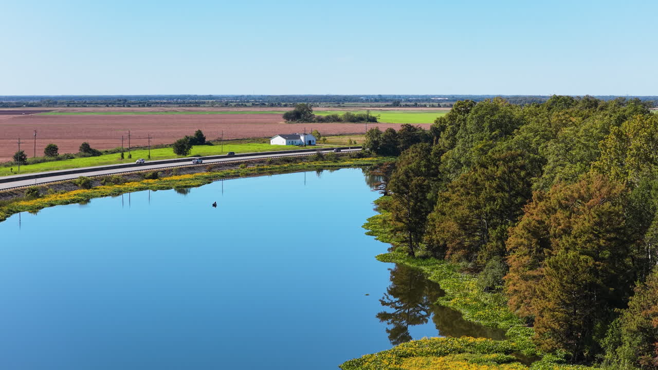 Rolig Noble-sø omkranset af træer og landbrugsjord, Pine Bluff, Arkansas; etablerende dronekredsløb.
