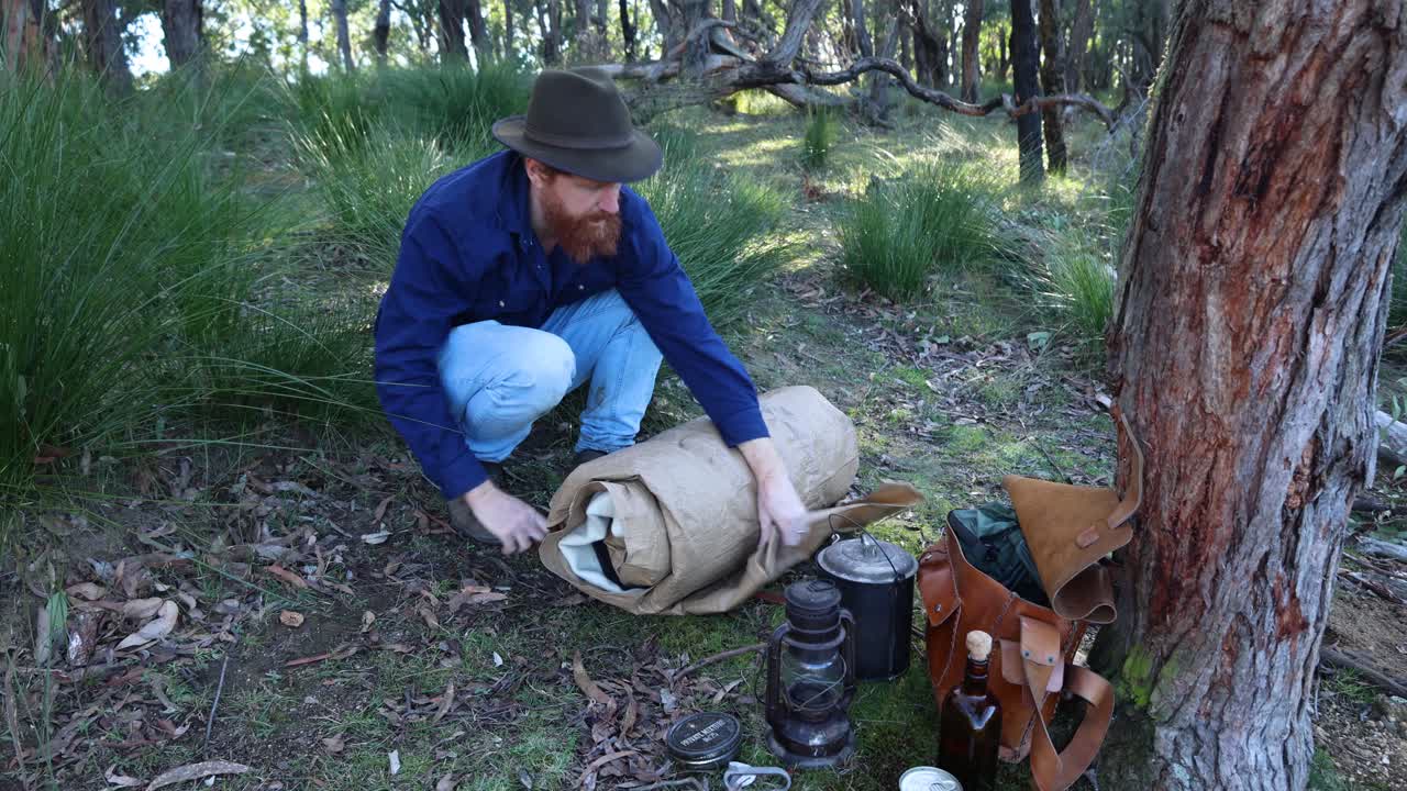 An Australian bush man rolls out his historic swag in the Australian bush