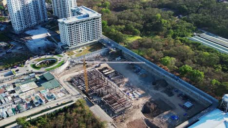 overhead drone shot of a construction area and yellow crane surrounded by city buildings and trees in manila, philippines