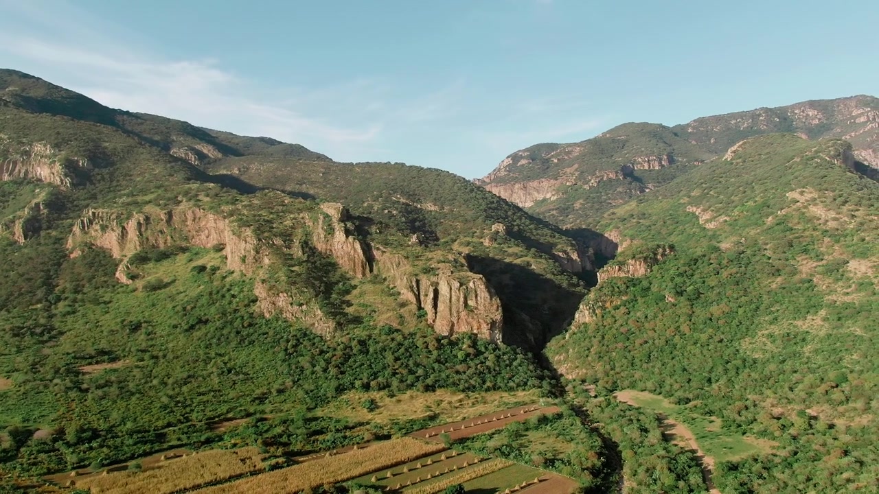 Cañón de la Garita con pareti rocciose del canyon, fitta vegetazione verde, campi coltivati e creste montuose vicino a Sierra Pénjamo, Guanajuato, Messico.