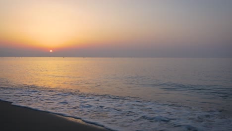 the sun goes beyond the horizon on the seashore and is reflected in the waves