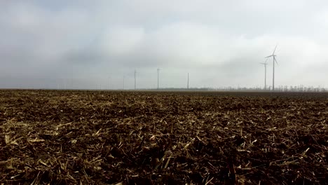 Langsame-Drohnenfahrt-über-Geräumtes-Mystisches-Maisfeld-Mit-Windkraftanlagen-Im-Burgenland,-Österreich