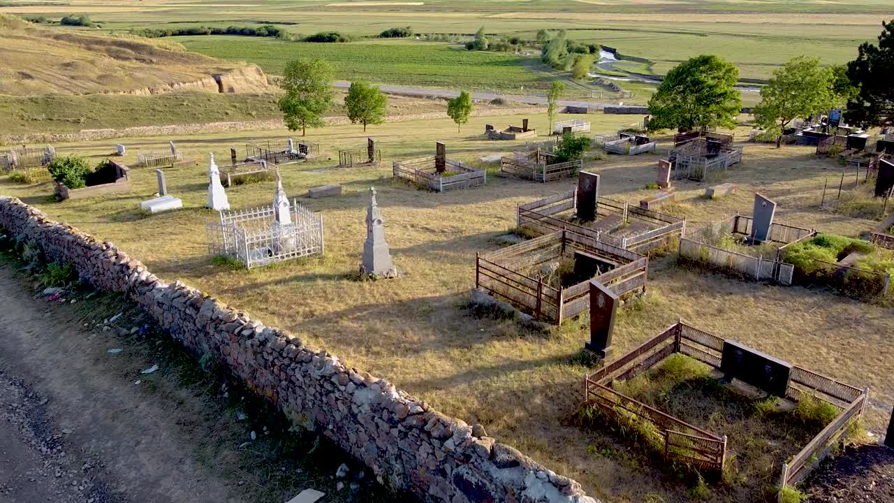 Discover an enchanting cemetery nestled in the countryside with historic gravestones. The area is captivating during sunset, offering a peaceful atmosphere among nature