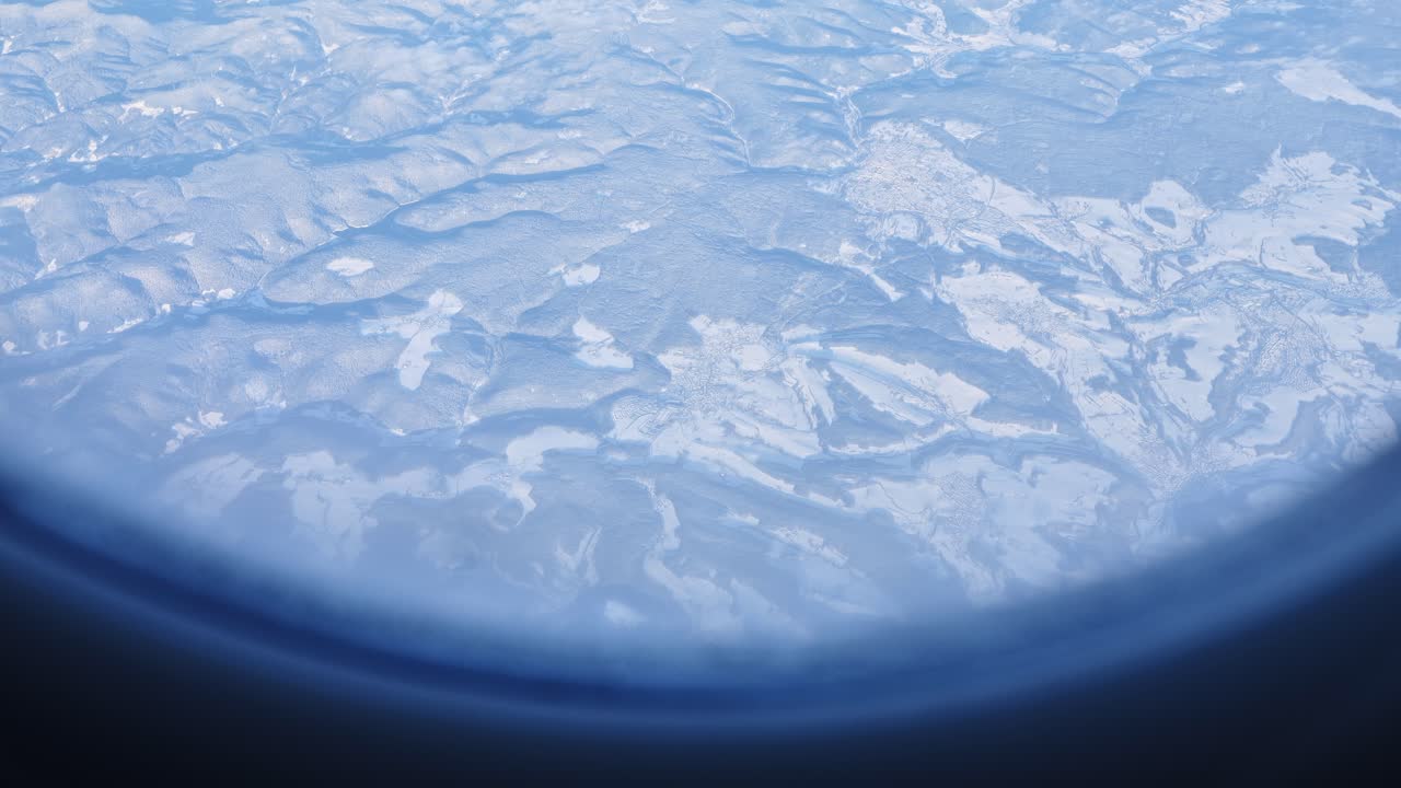 Frozen peaks and valleys of the Alps stretch beneath airplane window in daylight