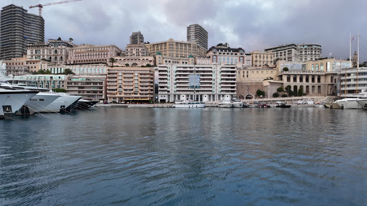 La Condamine, Monaco - July 4, 2025: Row of sleek luxury yachts, docked in Port Hercules with the Monaco cityscape and misty hills in the background