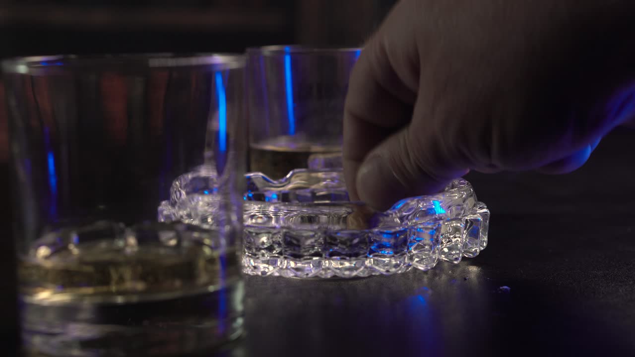 Rygning af cigaretter i lukket rum, whiskeyglas og hånd slukker cigaret og efterlader skod