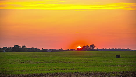 sunset timelapse over farm landscape with vibrant yellow and orange sky