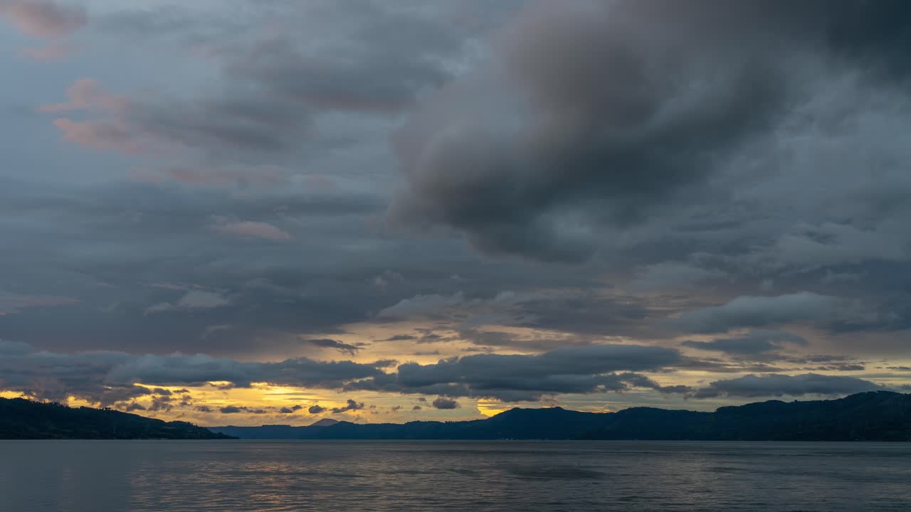 Cloudy Sunset over Water and Mountains