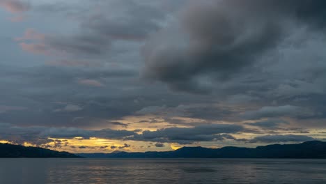 cloudy sunset over water and mountains