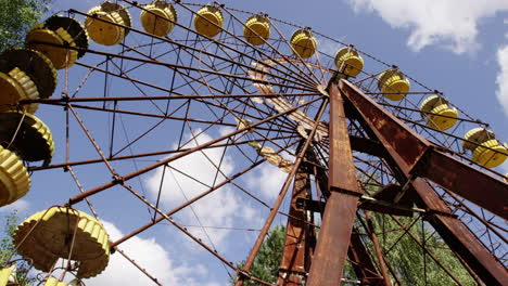 rustic ferris wheel with yellow baskets against blue sky, pripyat