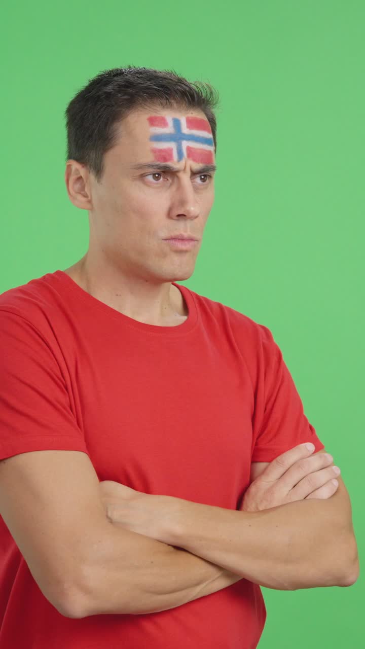 Man with norwegian flag painted looking away with serious expression