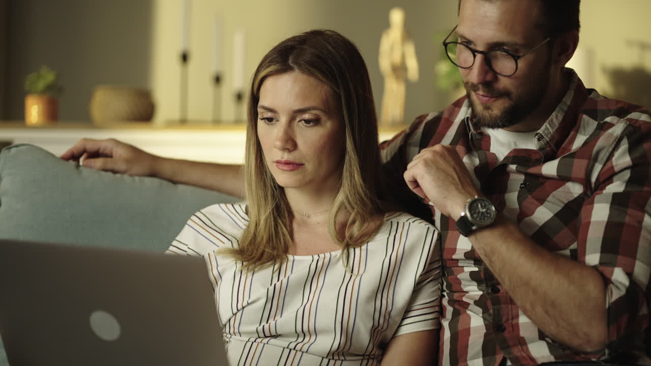 una pareja usando una computadora portátil en el sofá.