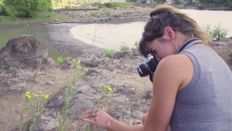 a cute hipster girl taking photos of flowers on a film camera