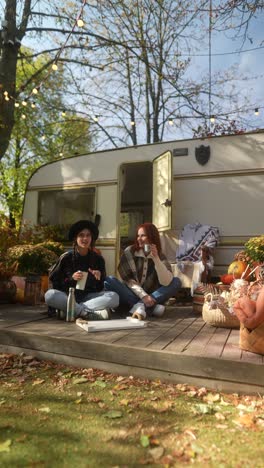 friends relaxing in autumn garden by camper