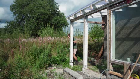 recorte de las plantas silvestres alrededor del invernadero en indre fosen, noruega - toma estática