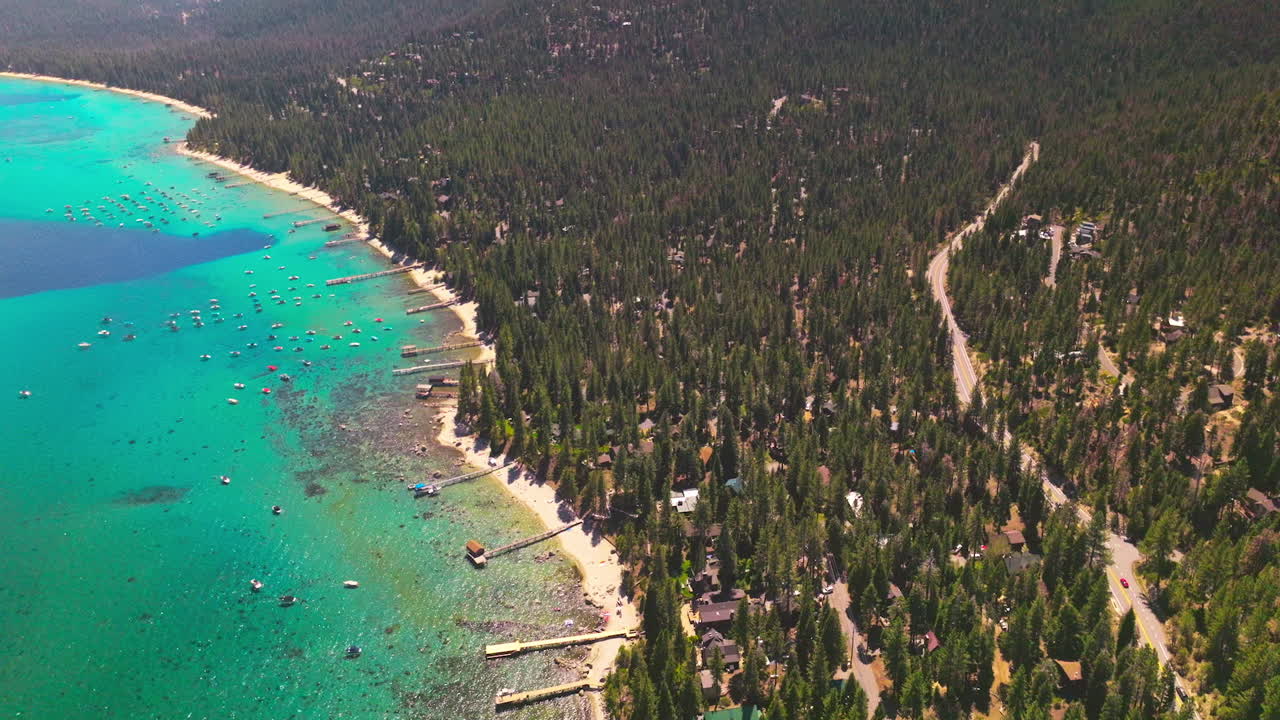 Adorable scenery of Lake Tahoe blue water and wooded shore of pine trees. Sunny footage of amazing nature from air.