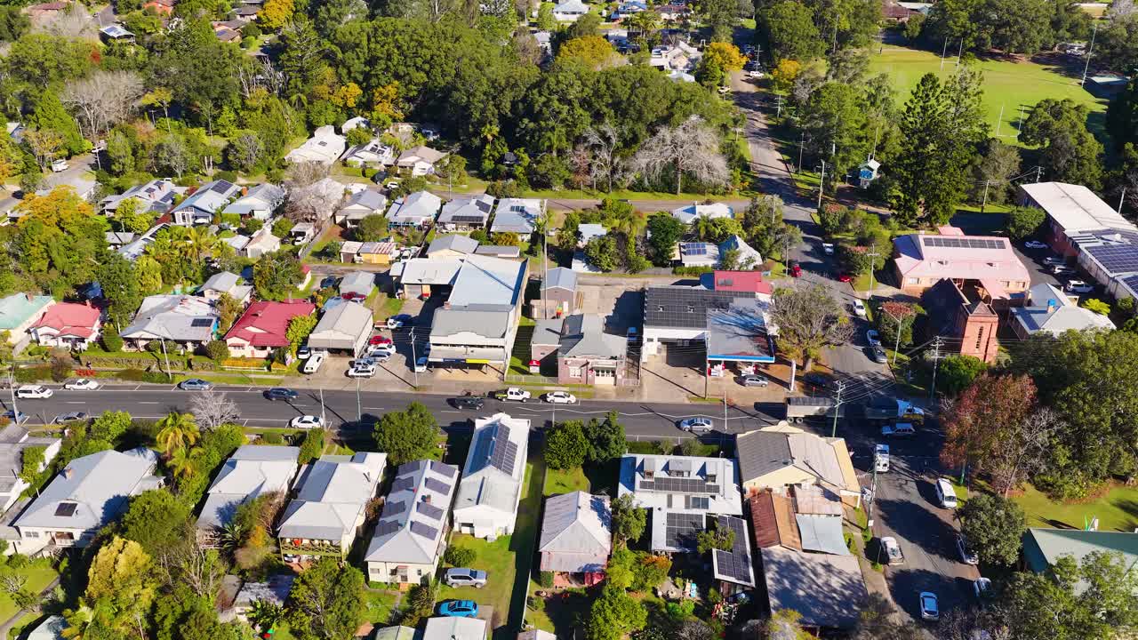 Imagem de drone em ângulo elevado captura um bairro residencial ensolarado com painéis solares e árvores verdes