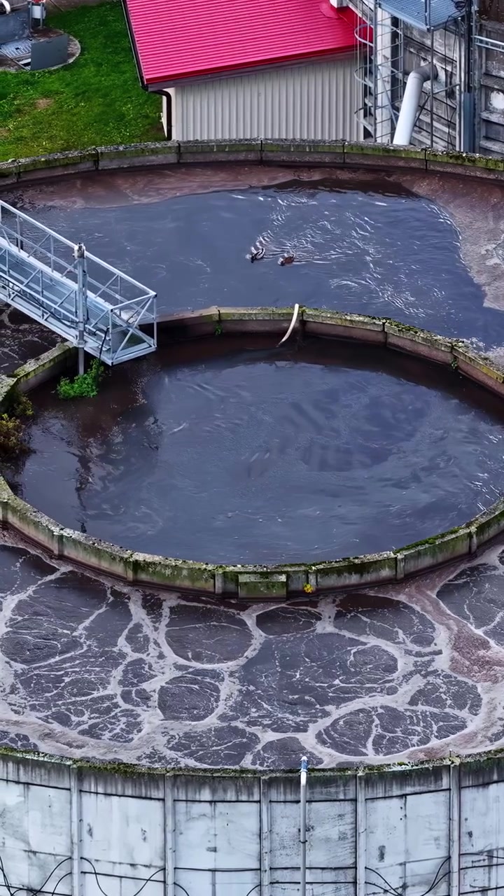 Vista aérea de una balsa circular de tratamiento de agua con agitación superficial al aire libre.