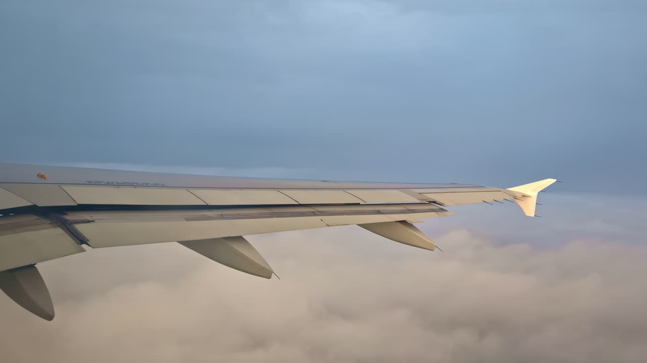 View Of Airplane Wing While Flying Above Sea Of Clouds During Daytime. POV shot
